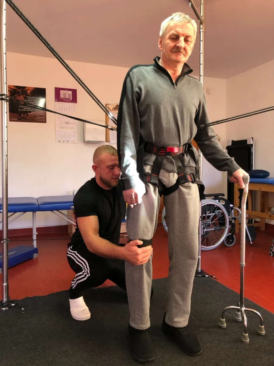 Terapeuta asystuje pacjentowi podczas ćwiczeń stania w Ośrodku Norman